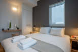 Cozy bedroom with a comfortable double bed, crisp white linens, and a soft gray throw blanket.