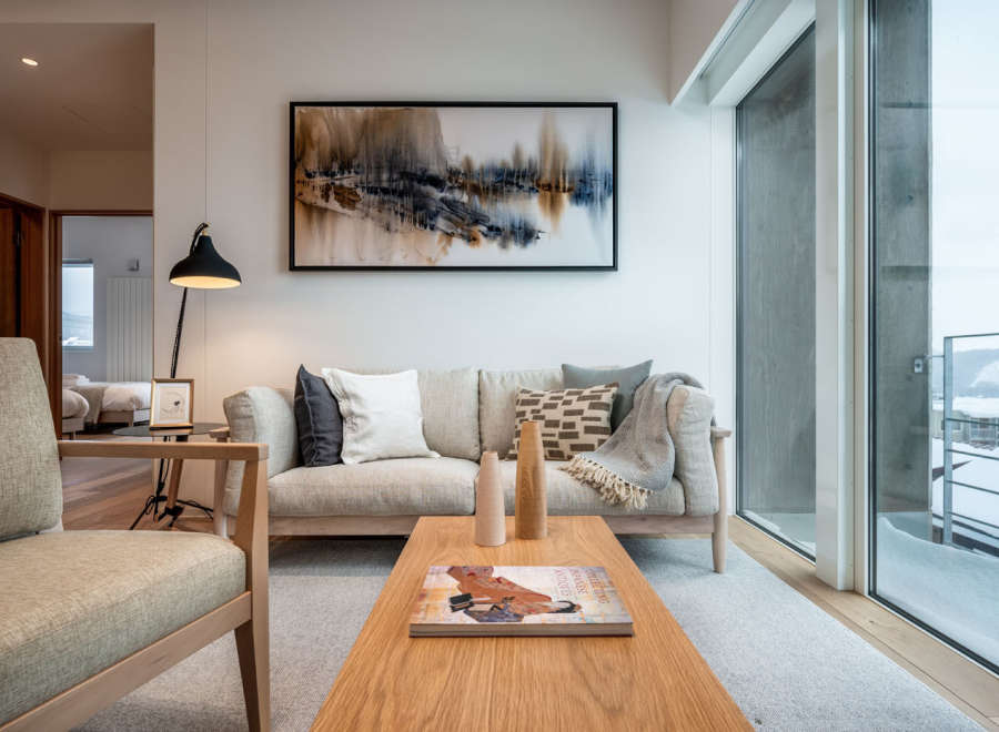 Modern living room with large windows offering stunning views of a snow-covered landscape.