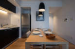 Modern apartment boasts an open-plan kitchen and dining area, featuring sleek black cabinetry, stainless steel appliances, and a light wood dining table.