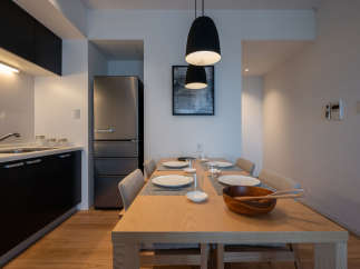 Modern apartment boasts an open-plan kitchen and dining area, featuring sleek black cabinetry, stainless steel appliances, and a light wood dining table.