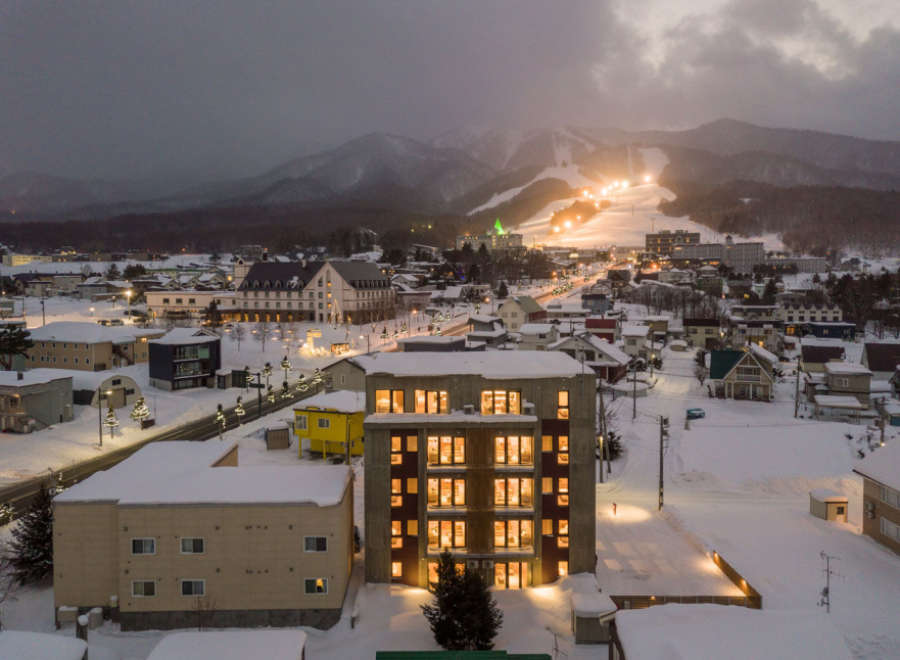 This stunning property boasts a prime location in a snow-covered town, offering breathtaking views of a nearby ski resort illuminated at night.