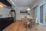 This modern apartment boasts an open-plan kitchen with sleek dark cabinetry and integrated appliances, seamlessly flowing into a dining area with a light wood table and comfortable seating.