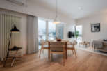 This modern apartment boasts an open-plan living area with hardwood floors, large windows offering scenic views, and a stylish dining set.