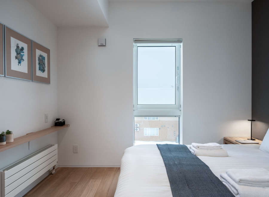 This bright and airy bedroom features a comfortable queen-size bed with crisp white linens and a cozy gray throw.