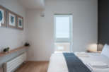 This bright and airy bedroom features a comfortable queen-size bed with crisp white linens and a cozy gray throw.