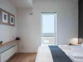 This bright and airy bedroom features a comfortable queen-size bed with crisp white linens and a cozy gray throw.