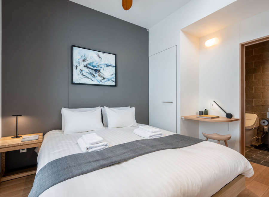 This cozy bedroom features a comfortable double bed with crisp white linens and a plush gray throw, perfect for a relaxing stay.