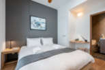 This cozy bedroom features a comfortable double bed with crisp white linens and a plush gray throw, perfect for a relaxing stay.
