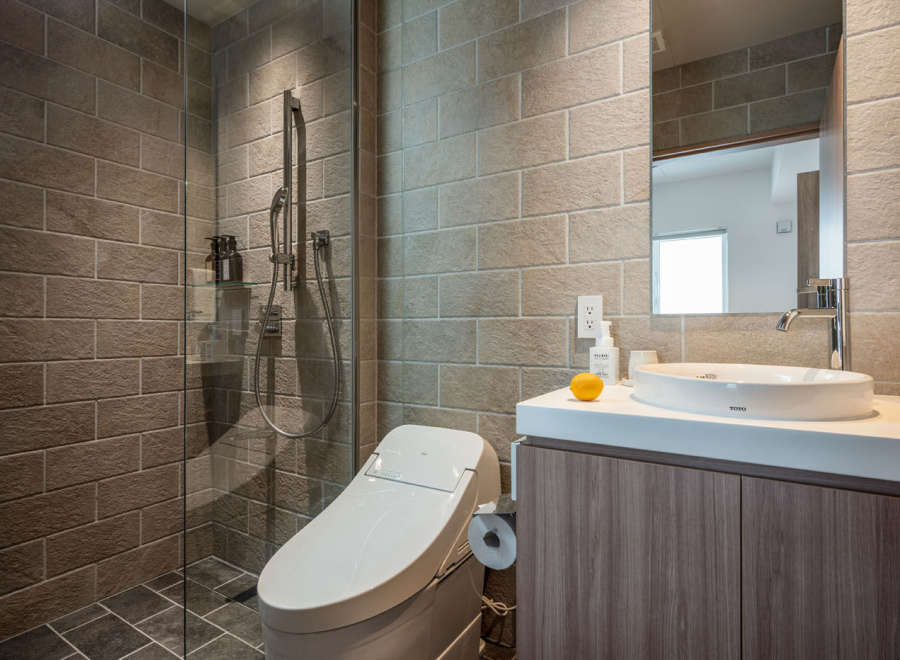 This modern bathroom boasts a sleek, minimalist design with a walk-in shower, a Toto toilet, and a stylish sink vanity.
