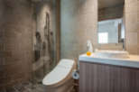 This modern bathroom boasts a sleek, minimalist design with a walk-in shower, a Toto toilet, and a stylish sink vanity.