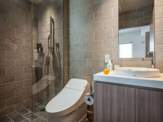This modern bathroom boasts a sleek, minimalist design with a walk-in shower, a Toto toilet, and a stylish sink vanity.