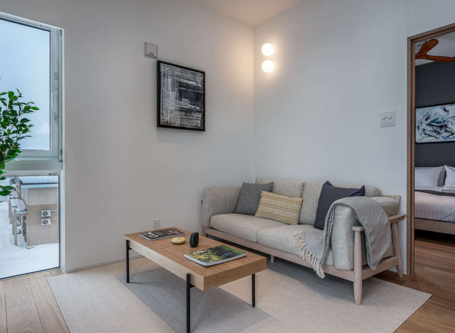 This modern apartment boasts a light and airy living space, featuring a comfortable sofa with plush pillows and a stylish coffee table.