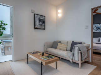 This modern apartment boasts a light and airy living space, featuring a comfortable sofa with plush pillows and a stylish coffee table.