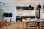 Modern apartment boasts an open-plan kitchen and living area, featuring sleek black cabinetry, integrated appliances, and a light wood dining table.