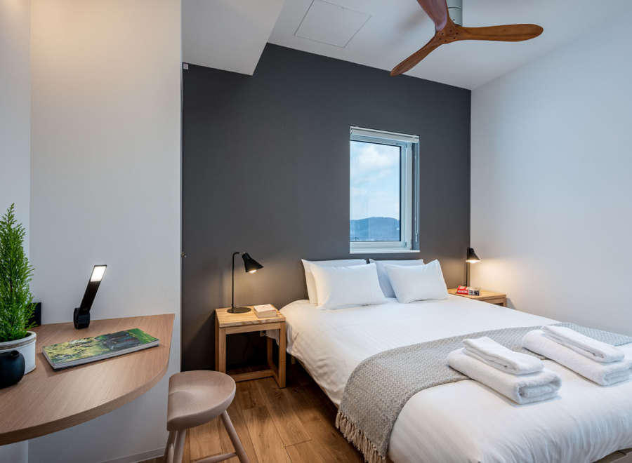 This cozy bedroom features a comfortable double bed with crisp white linens and a soft gray throw, perfect for a relaxing stay.