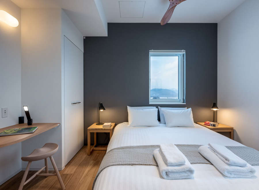 This modern bedroom features a comfortable queen-size bed with crisp white linens and plush gray throw blanket.
