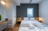 This modern bedroom features a comfortable queen-size bed with crisp white linens and plush gray throw blanket.