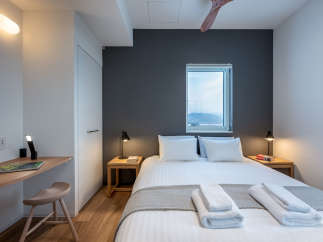 This modern bedroom features a comfortable queen-size bed with crisp white linens and plush gray throw blanket.