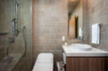 This modern bathroom boasts a sleek, minimalist design with a walk-in shower, a toilet, and a stylish vanity with a vessel sink.