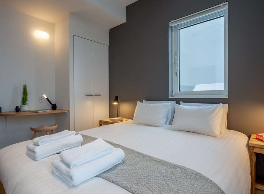 Cozy bedroom with a comfortable double bed, crisp white linens, and a soft gray throw blanket.
