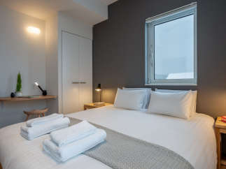Cozy bedroom with a comfortable double bed, crisp white linens, and a soft gray throw blanket.
