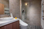 This modern bathroom boasts a sleek design with beige brick walls and dark gray floor tiles.