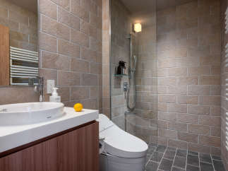 This modern bathroom boasts a sleek design with beige brick walls and dark gray floor tiles.