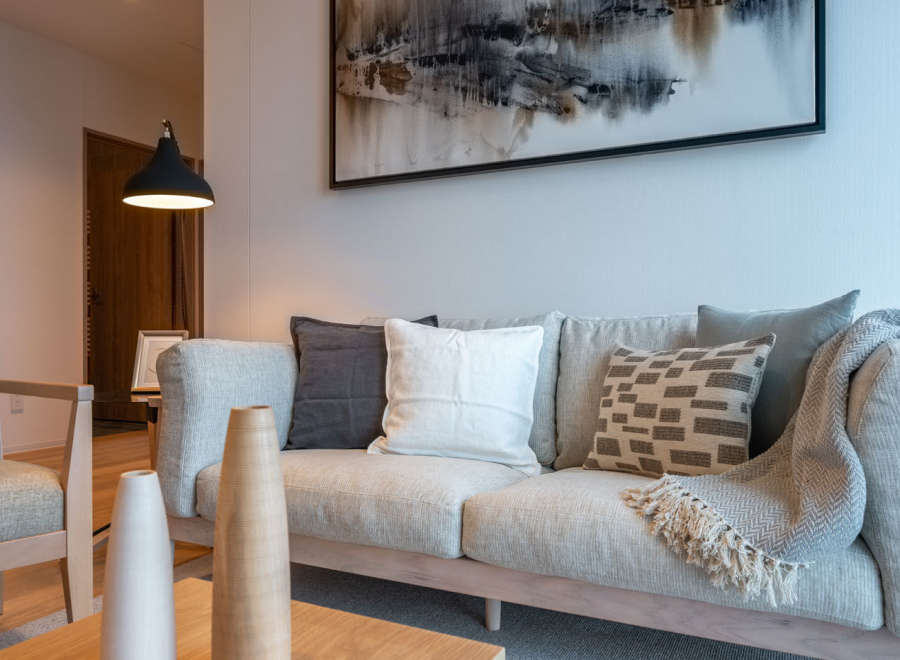 This stunning living room features a light grey sofa adorned with plush pillows and a cozy throw blanket, creating a serene atmosphere.