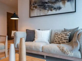 This stunning living room features a light grey sofa adorned with plush pillows and a cozy throw blanket, creating a serene atmosphere.