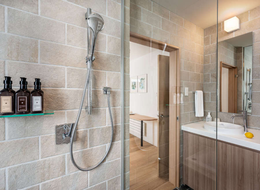 This modern bathroom boasts a sleek glass-enclosed shower with rainfall showerhead and a stylish vanity with a vessel sink.