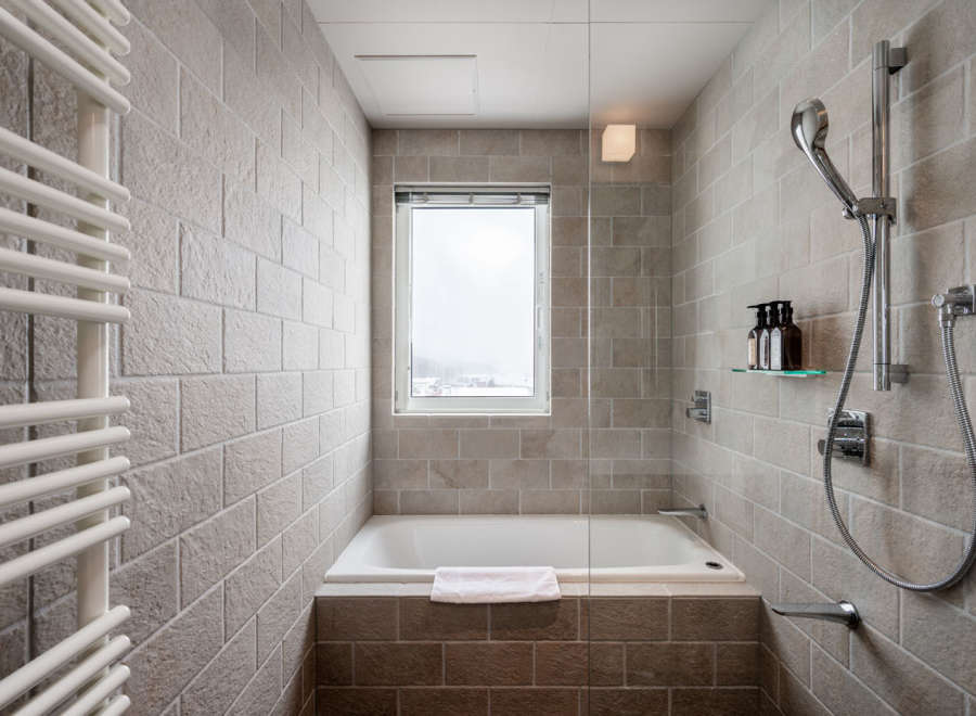 This modern bathroom boasts a sleek design with a built-in bathtub, a rainfall showerhead, and a heated towel rack.