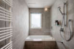This modern bathroom boasts a sleek design with a built-in bathtub, a rainfall showerhead, and a heated towel rack.