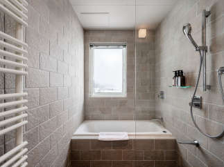 This modern bathroom boasts a sleek design with a built-in bathtub, a rainfall showerhead, and a heated towel rack.