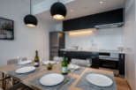 Modern kitchen and dining area with sleek black cabinetry, stainless steel appliances, and stylish pendant lighting.