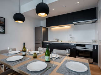 Modern kitchen and dining area with sleek black cabinetry, stainless steel appliances, and stylish pendant lighting.