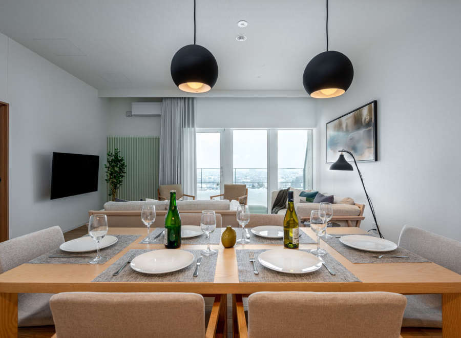 Modern apartment boasts an open-plan living and dining area with floor-to-ceiling windows offering stunning city views.