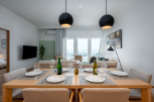 Modern apartment boasts an open-plan living and dining area with floor-to-ceiling windows offering stunning city views.