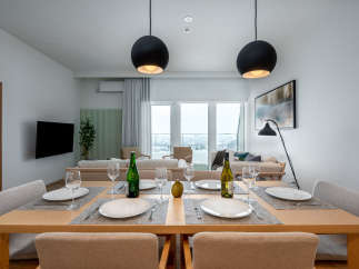 Modern apartment boasts an open-plan living and dining area with floor-to-ceiling windows offering stunning city views.