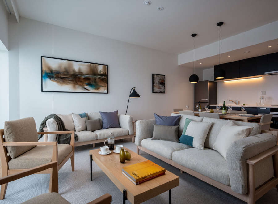 This stunning apartment boasts an open-plan living area with ample natural light, featuring comfortable sofas and armchairs perfect for relaxation.