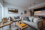 This stunning apartment boasts an open-plan living area with ample natural light, featuring comfortable sofas and armchairs perfect for relaxation.