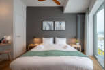 This modern bedroom boasts a king-size bed with crisp white linens and a plush green throw, complemented by minimalist nightstands and stylish artwork.