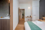 This modern bedroom features a minimalist design with light wood flooring and a neutral color palette.