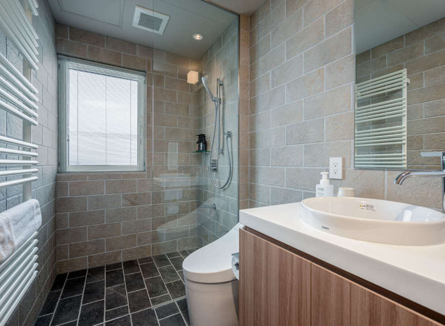 This modern bathroom boasts a spacious shower with glass enclosure, a sleek Toto sink and vanity, and heated towel racks for ultimate comfort.