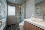This modern bathroom boasts a spacious shower with glass enclosure, a sleek Toto sink and vanity, and heated towel racks for ultimate comfort.