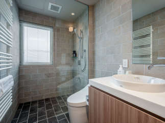 This modern bathroom boasts a spacious shower with glass enclosure, a sleek Toto sink and vanity, and heated towel racks for ultimate comfort.