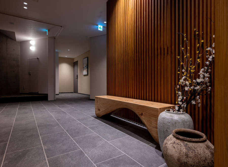 This modern hotel boasts a stylish hallway with a sleek wooden bench and unique ceramic pots, creating a serene atmosphere.