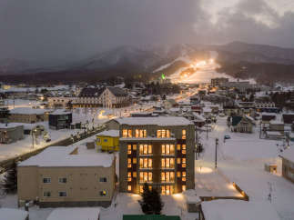 This stunning property boasts a prime location in a snow-covered town, offering breathtaking views of a nearby ski resort illuminated at night.