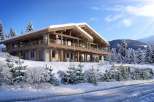Luxury chalet in the snowy Alps, boasting stunning mountain views and spacious wooden interiors.