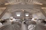 Rustic-chic chalet bedroom with exposed wooden beams and multiple beds, perfect for a family getaway.