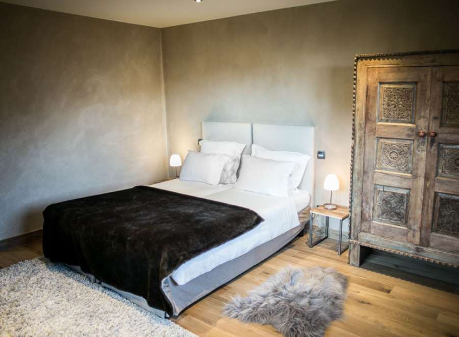 Cozy bedroom with a plush bed, soft rug, and intricately carved wooden wardrobe.